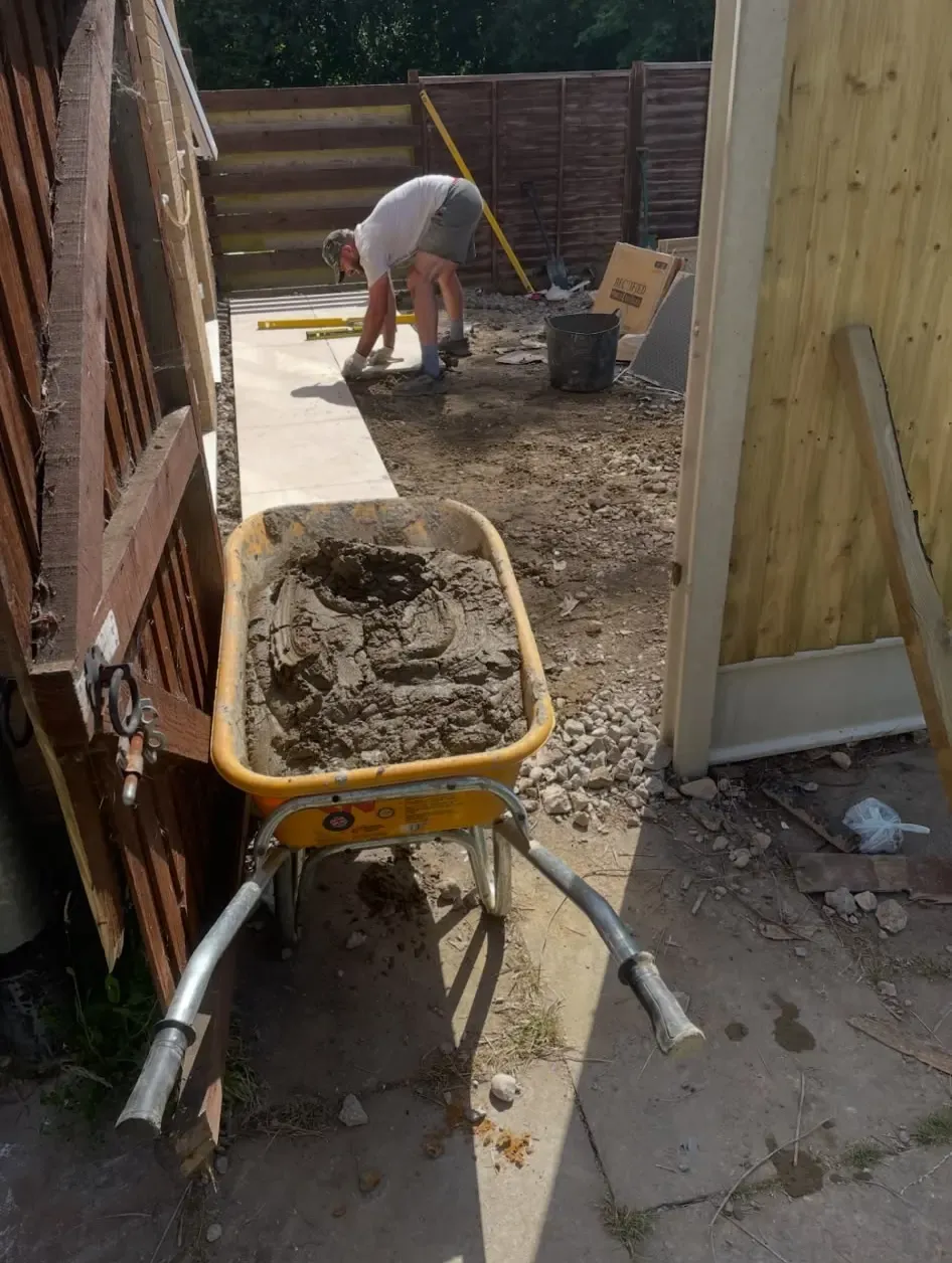 A landscaper from Swift Property Solutions expertly installing a new patio in a Northamptonshire garden
